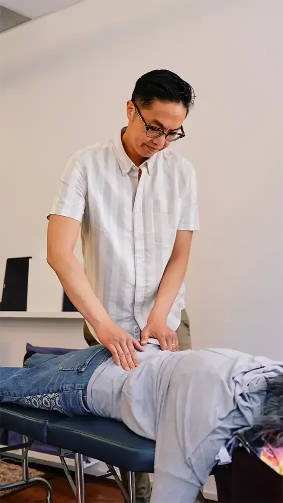 Dr. Leo performing a low back assessment on a patient lying face down on a treatment table.