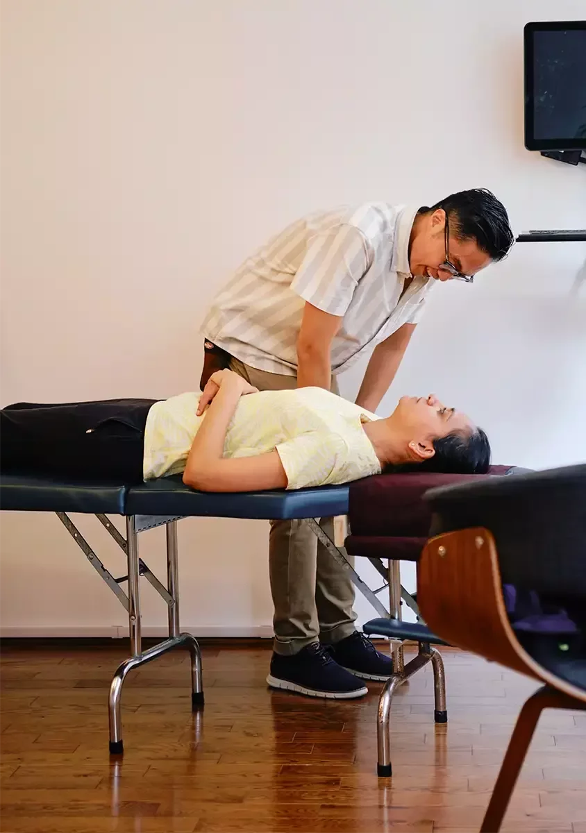 Chiropractor speaking with a patient lying on a treatment table at Source Chiropractic in Toronto.