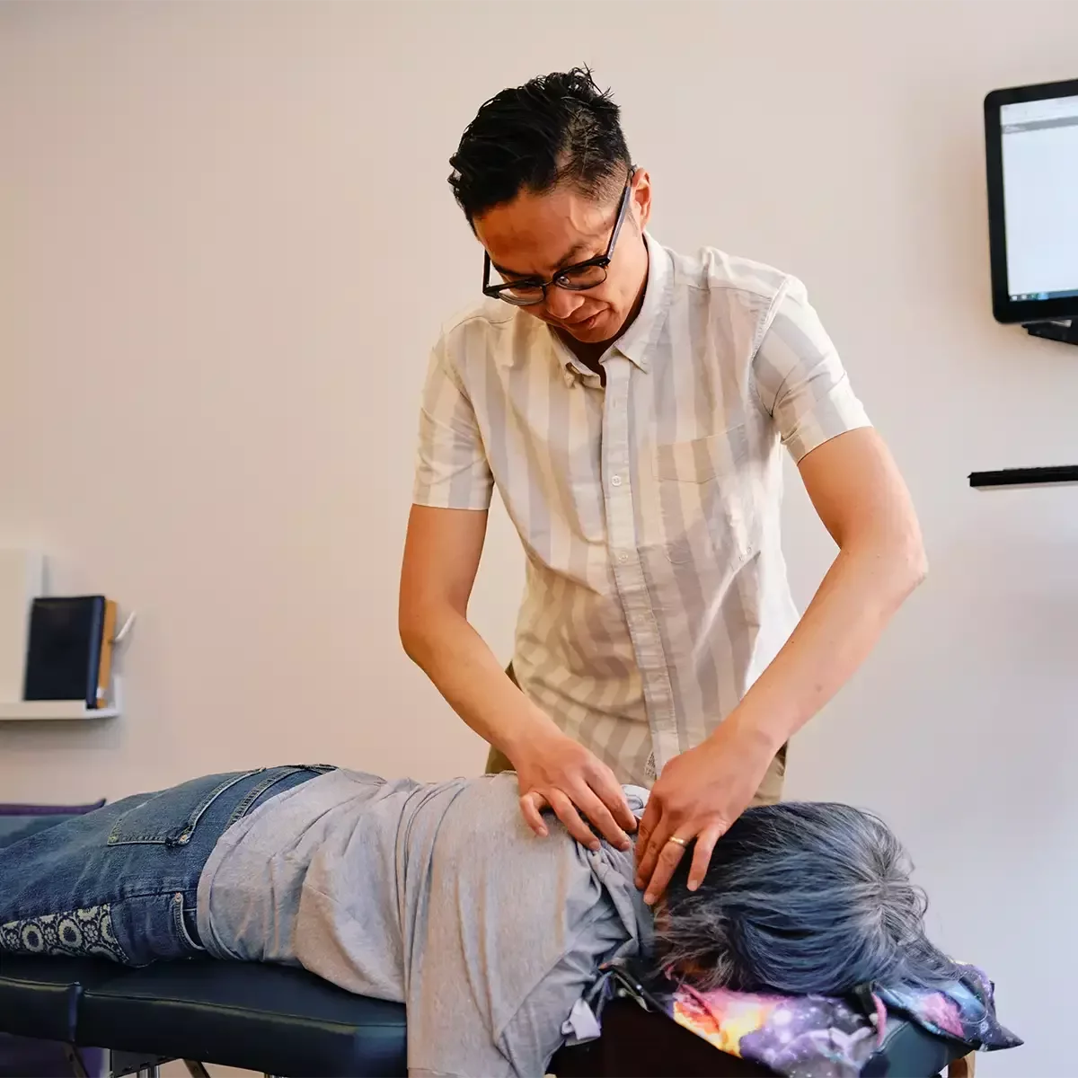 Dr. Leo Quan performing a gentle NetworkSpinal adjustment on a patient at Source Chiropractic in Toronto.