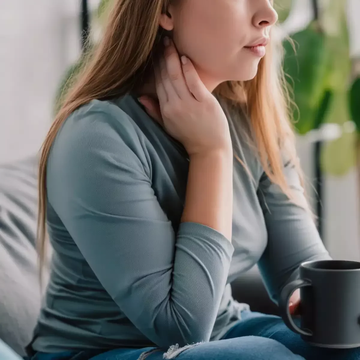 Person holding the side of their neck while experiencing morning neck stiffness at home.