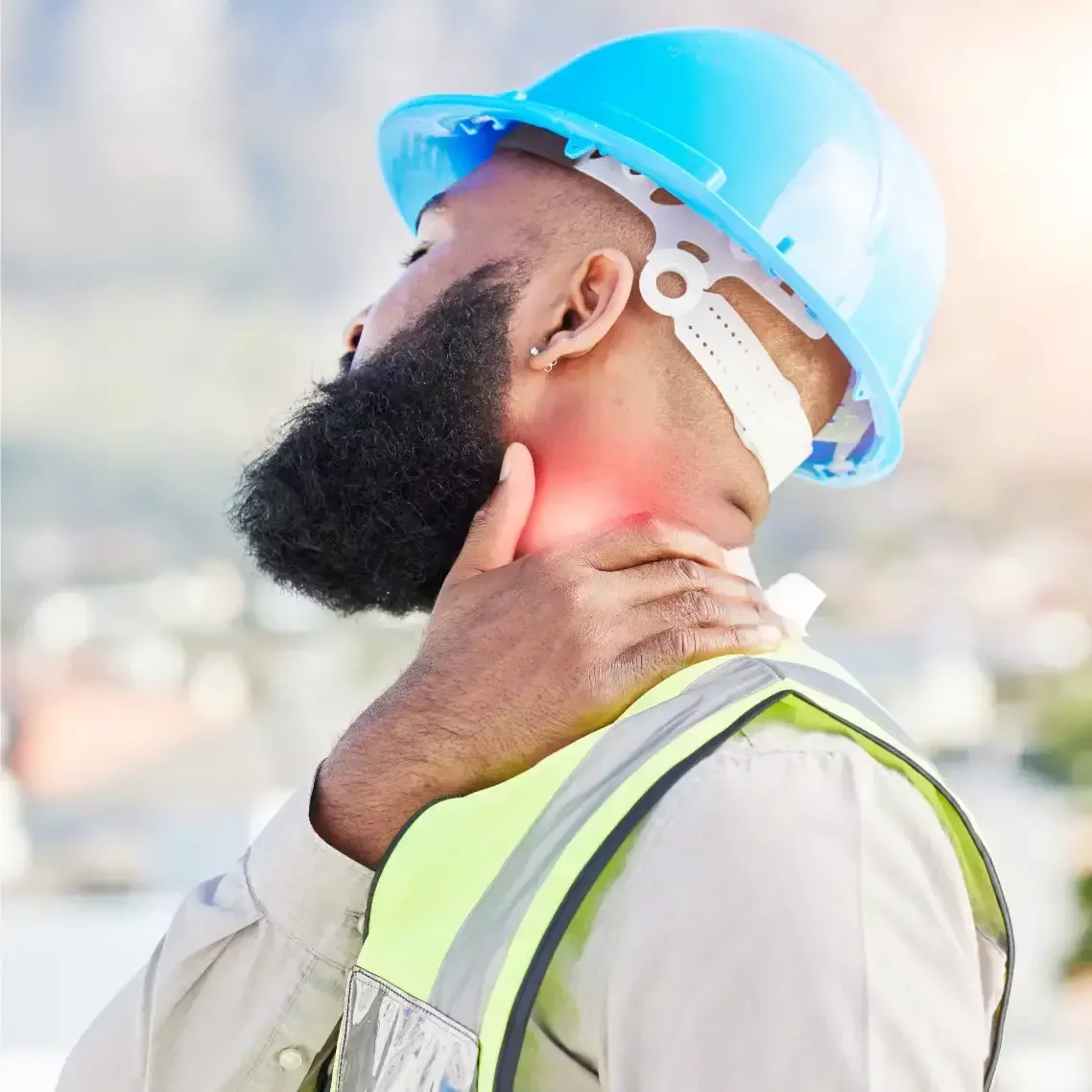 Construction worker experiencing neck pain while wearing a hard hat and safety vest.
