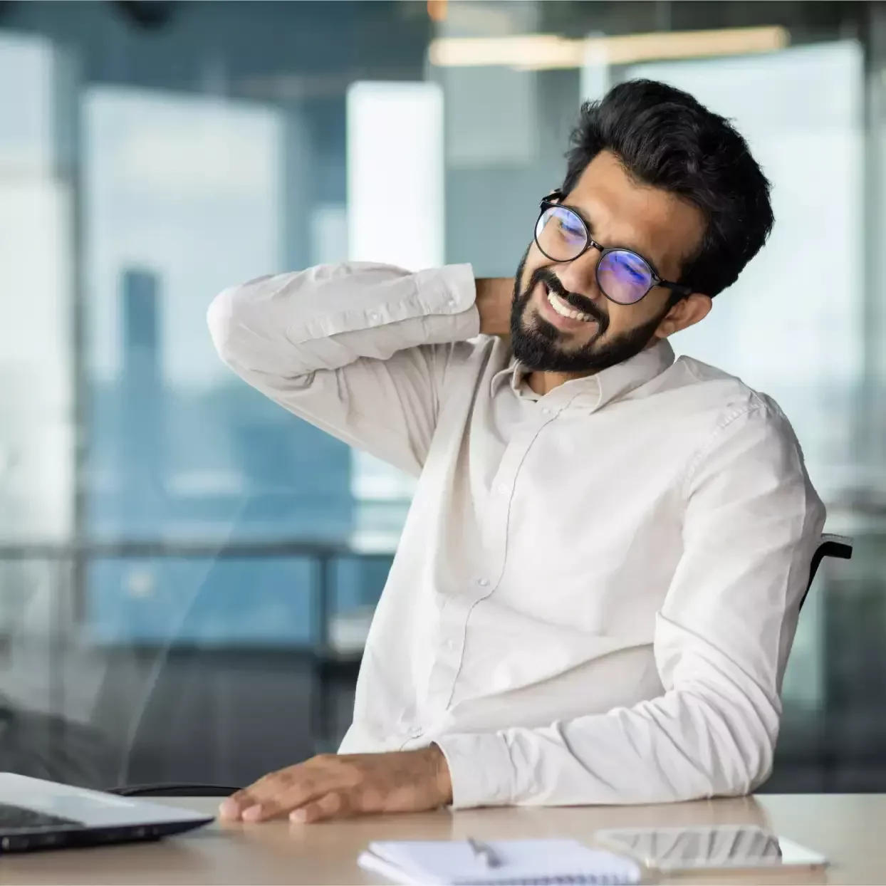 Office worker holding the back of his neck in discomfort while seated at a desk.